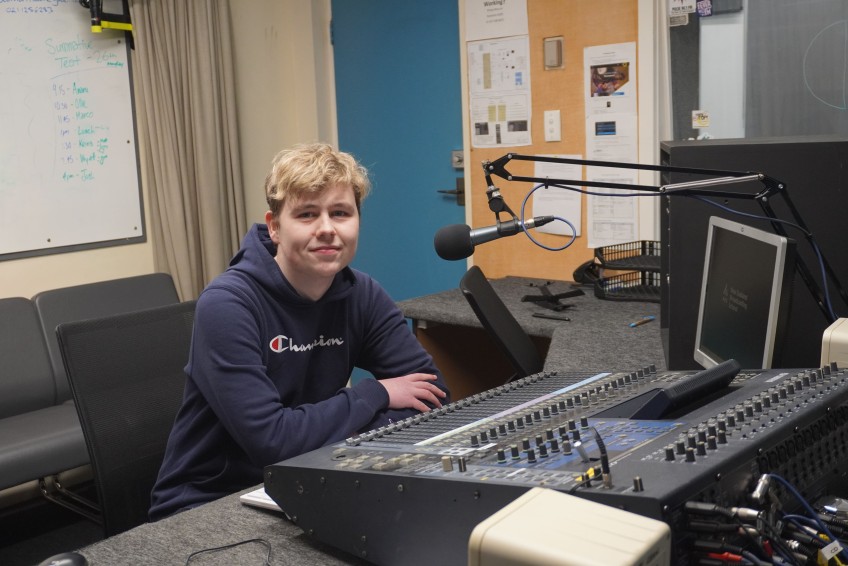Henderson smiling in a radio production booth
